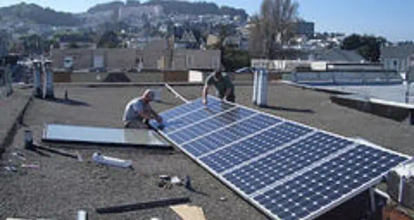 men installing solar panels on a roof