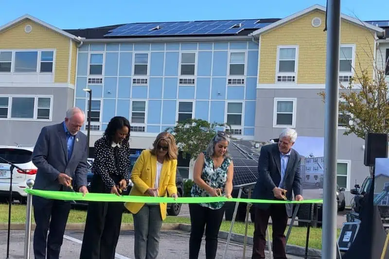 Sulzbacher Village ribbon cutting ceremony in front of a yellow, blue and gray building