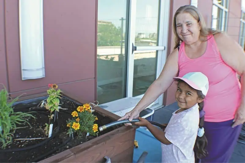 woman and young girl water flowers in a planter box