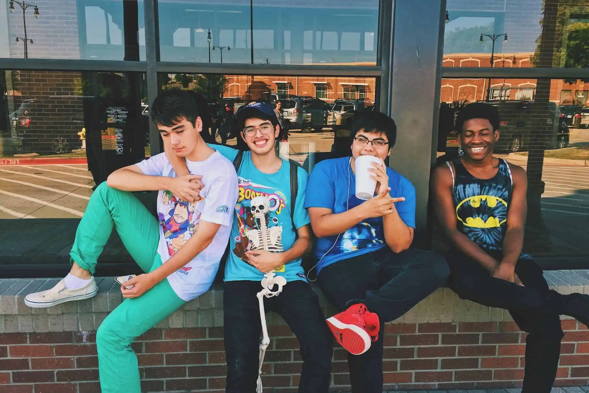 four boys sitting on a brick ledge smiling