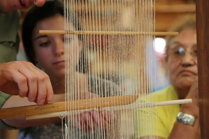 man showing a girl how to work on a loom