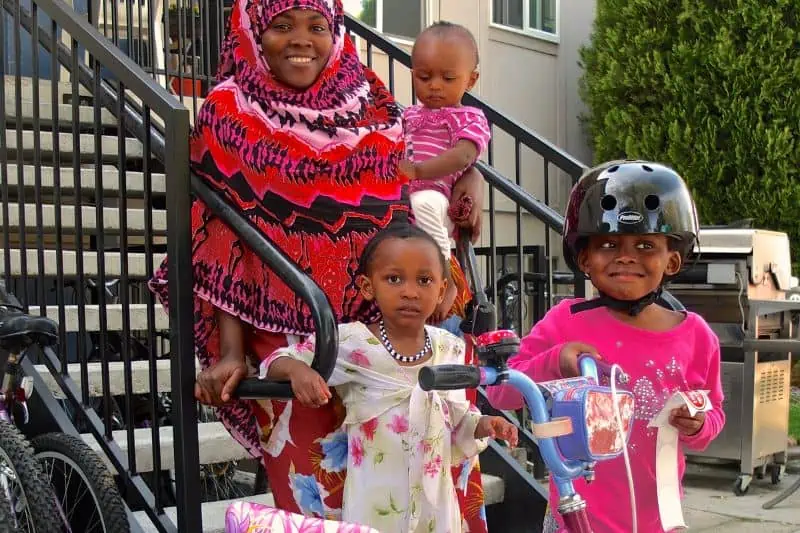 mom and three kids standing on the steps outside of an apartment building