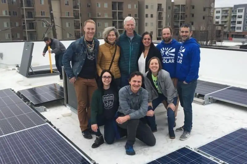 group of people standing on a roof with solar panels