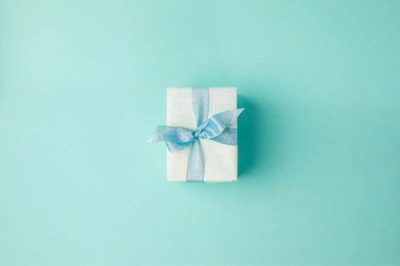 gift box with blue ribbon on teal background