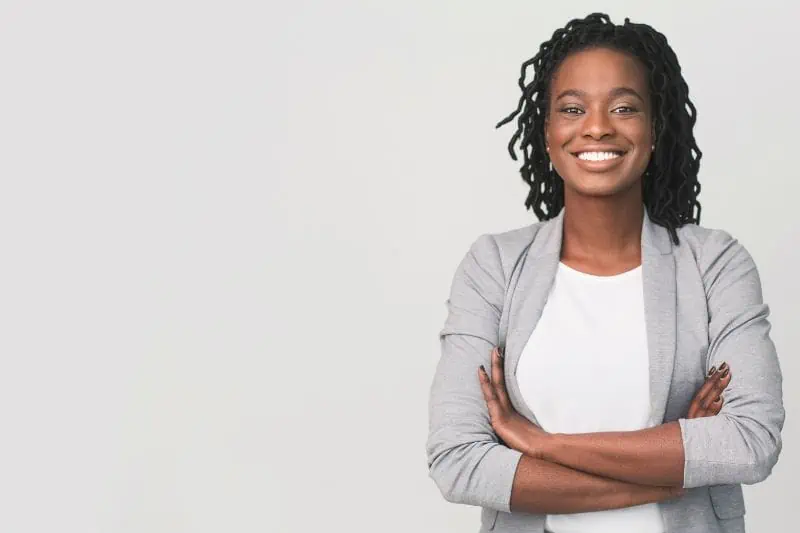 black woman smiling with arms folded on cream background