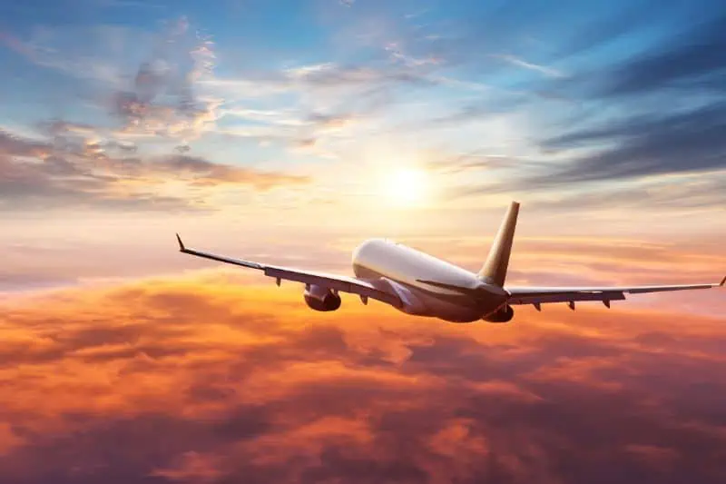 plane flying into sunset over orange clouds
