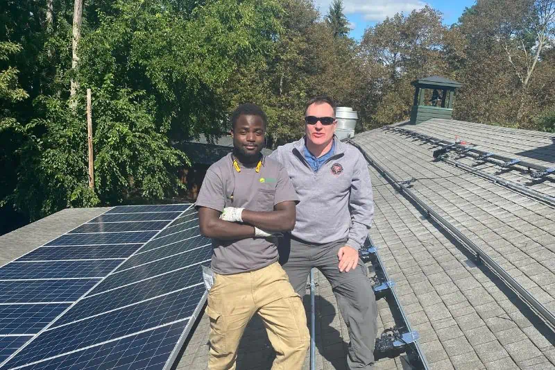 2 workers standing on a roof with solar panels