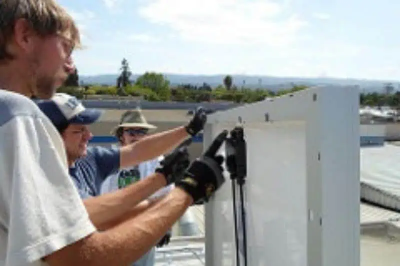 three men looking at solar panel