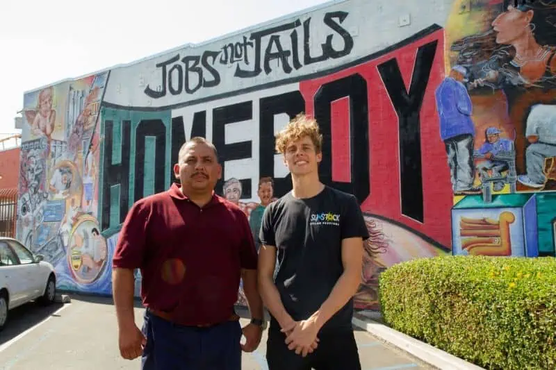 two men standing in front of a homeboy sign