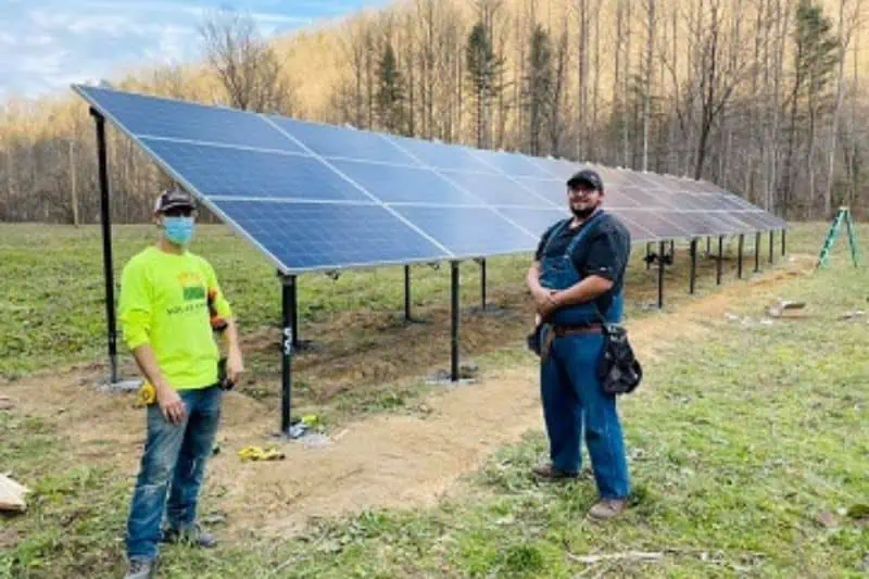 two workers standing next to newly installed solar panels