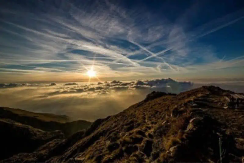 mountain with sun and clouds in the background