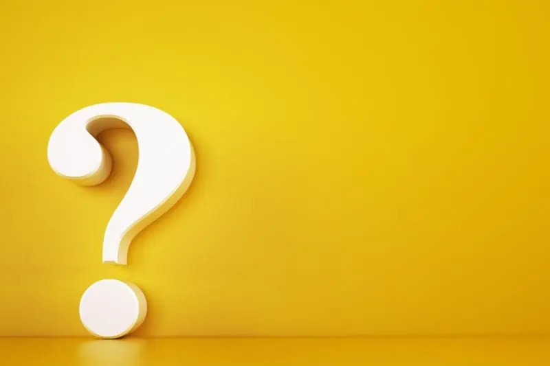 cream colored question mark against a yellow-orange wall