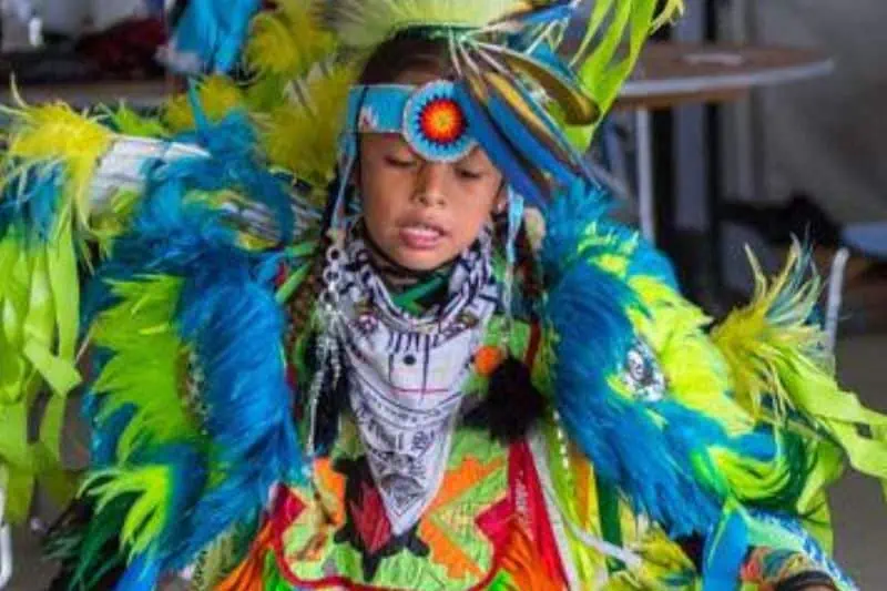 young boy dancing in bright native american dress