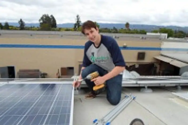 man looking at the camera while screwing in solar panels