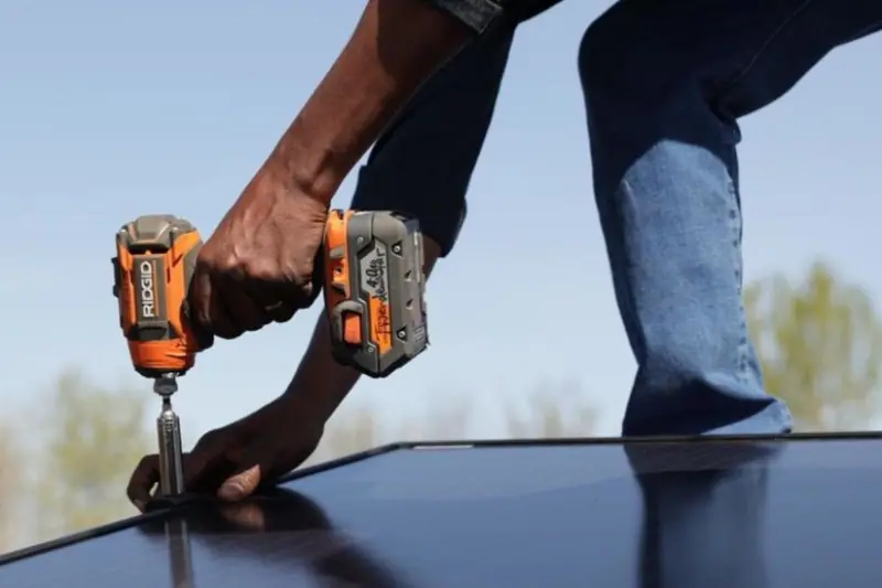 Hand holding drill and installing rooftop solar module