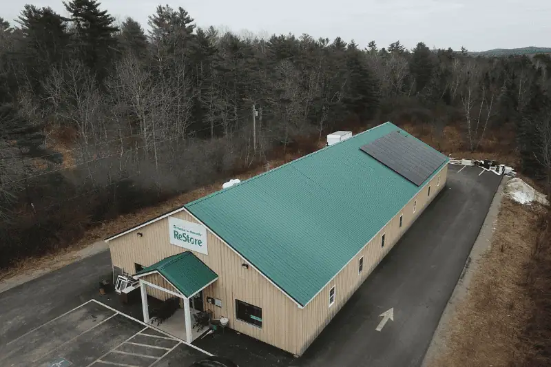 A picture of a one-story building with a green roof. On the roof there are solar panels installed. Picture is taken from a drone so a viewer can have a look at Habitat for Humanity Restore building from afar. 